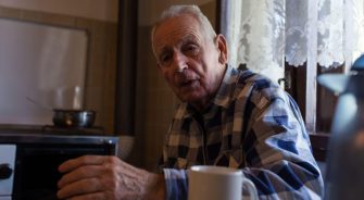 Senior man drinking tea at home in vintage interior of kitchen