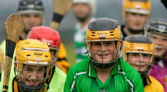 teenage boys wearing protective helmets line up for throw in before a practise hurling match holding camans sticks