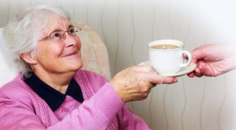 A sweet old woman being handed a coffee